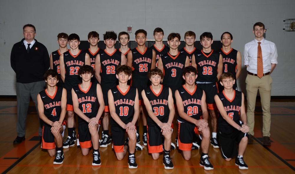 high school boys basketball team in black and orange uniforms with 2 coaches