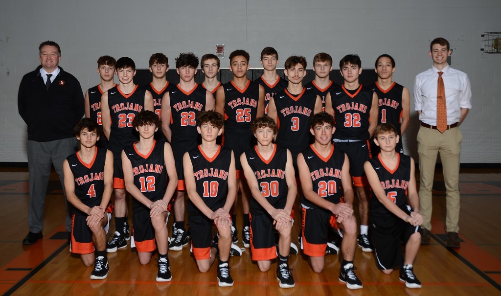 COHS basketball team in black and orange uniforms with 2 coaches