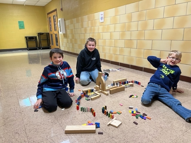3 boys sitting in a school hallway working with blocks