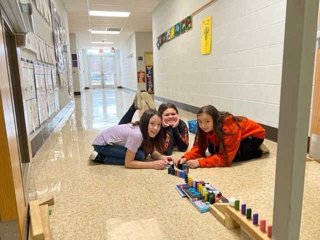 3 girls sitting in a school hallway working with blocks