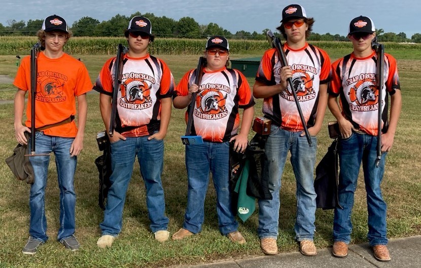 5 boys with caps, safety glasses, orange & black Claybreakers jerseys, and jeans holding their shotguns
