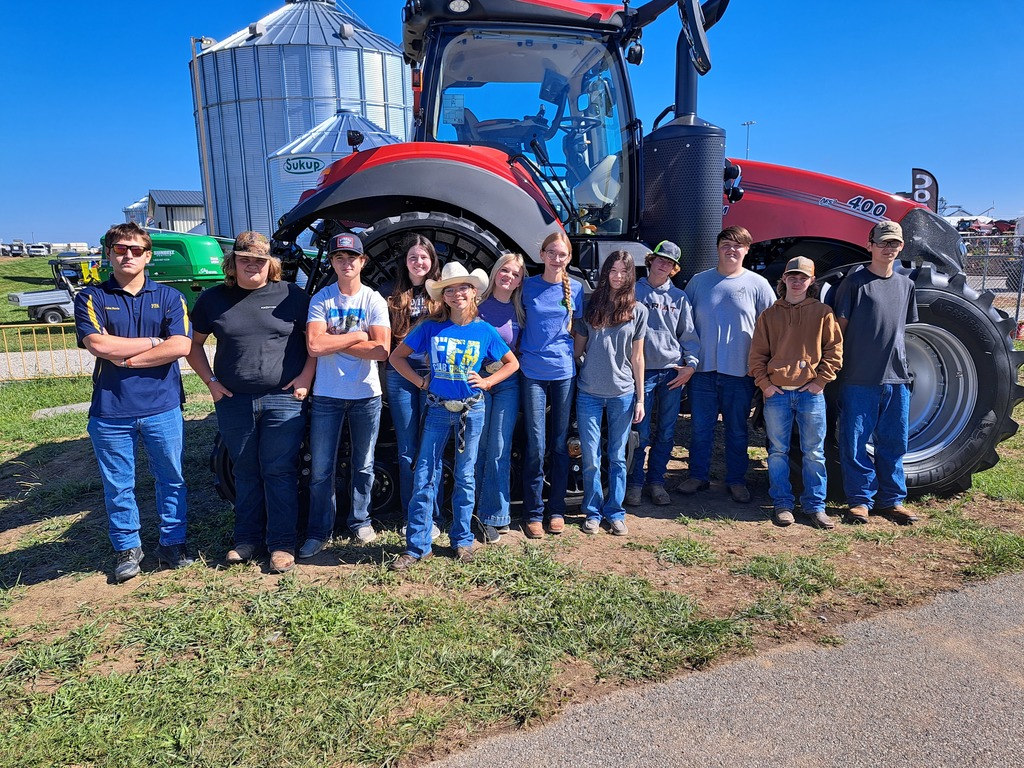 Students standing in front of large red tractor